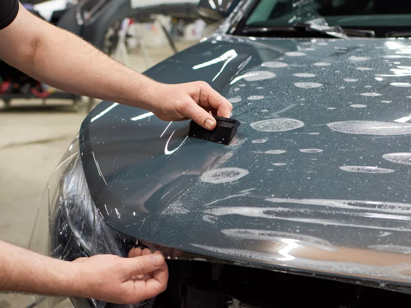 Paint protection film being squeegeed onto a vehicle hood