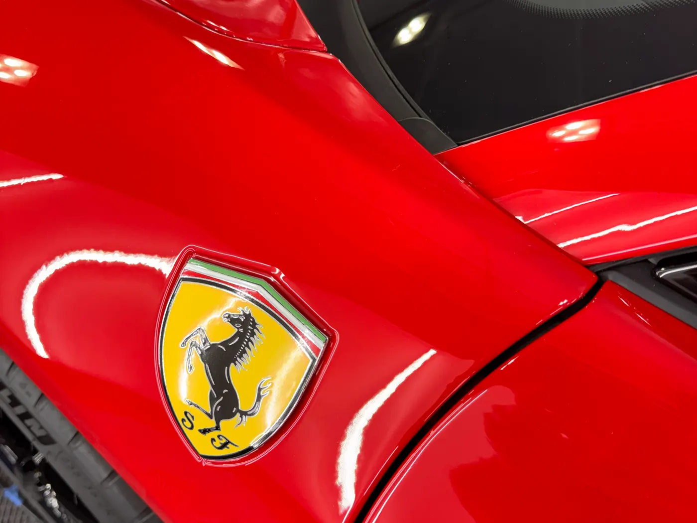 Paint protection film over the rear quarter panel and badge of a red Ferrari, installed by ACR Film Solutions